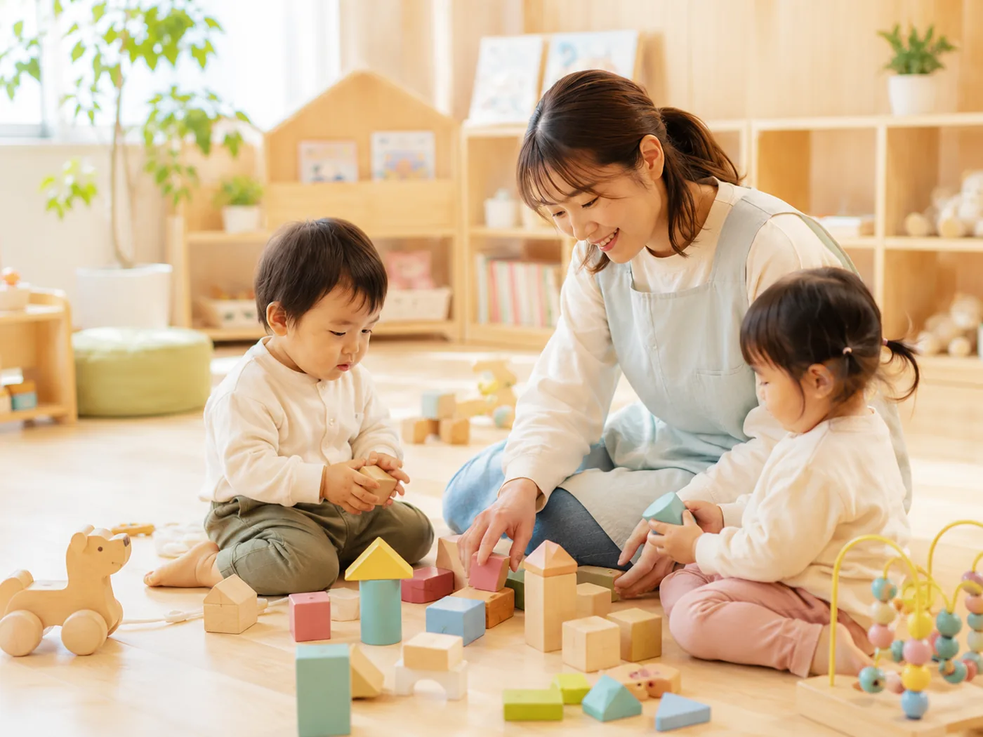 明るい保育室で過ごす子どもたちと保育士