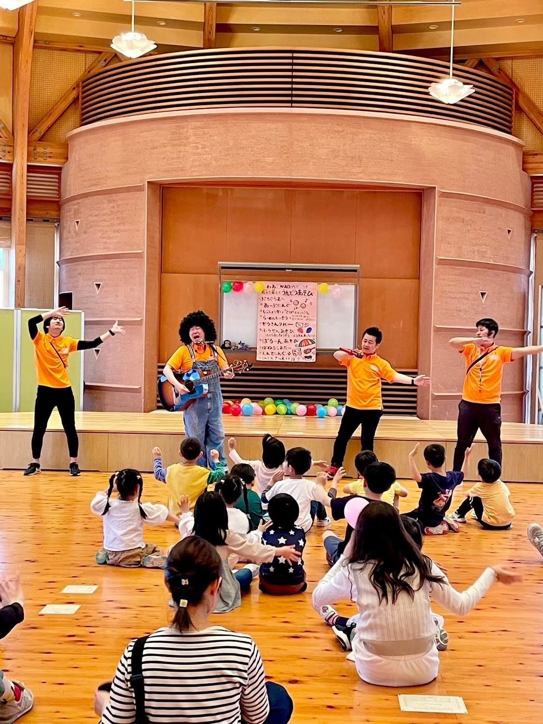 ホールで風船を飛ばして親子と遊ぶメンバーたち